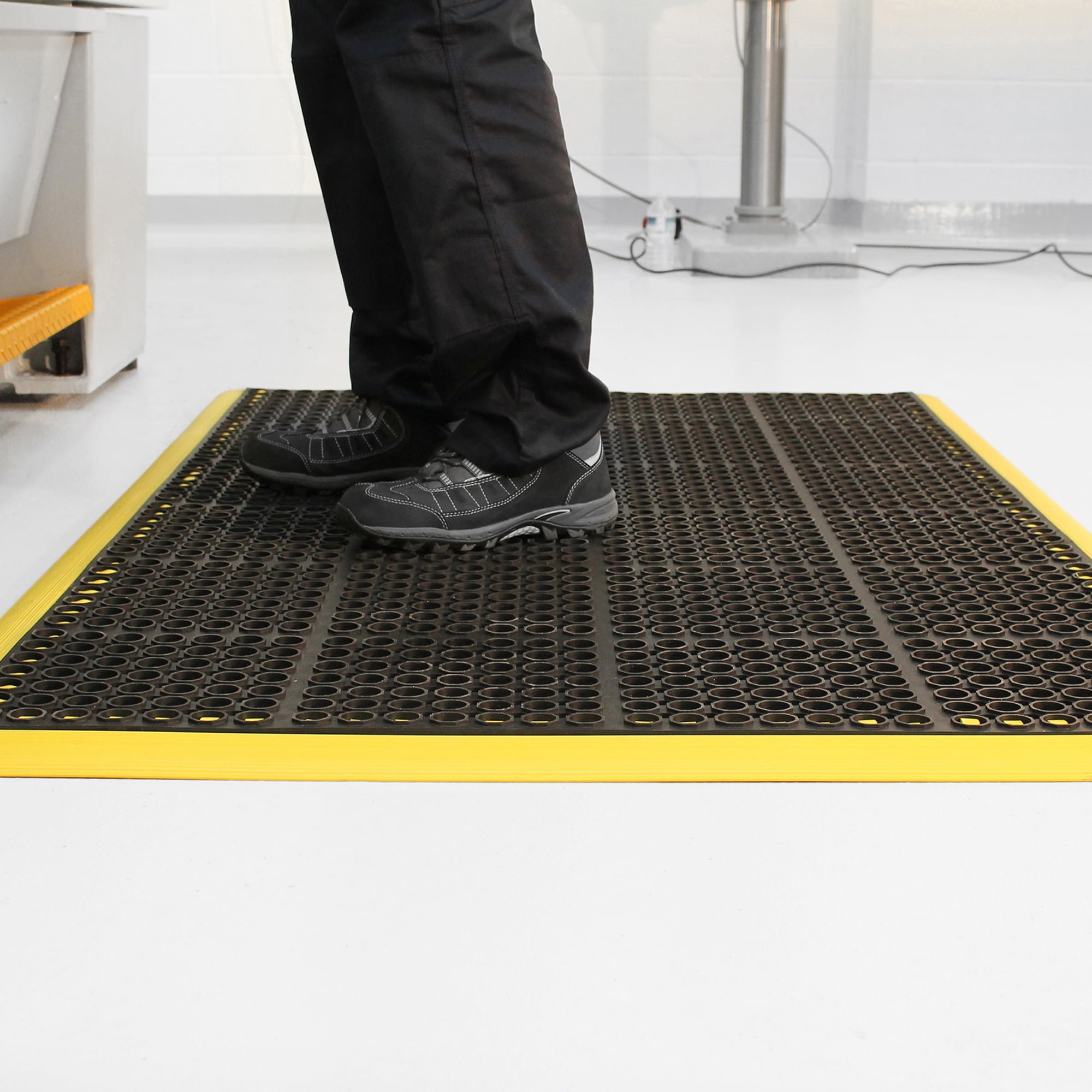 Worker-standing-on-a-black/yellow- COBAdeluxe-anti-fatigue-mat